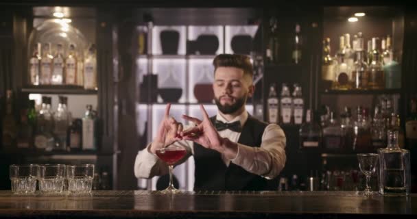 Barman vymačkává kousek pomerančové kůry a zdobí koktejl. 4k — Stock video