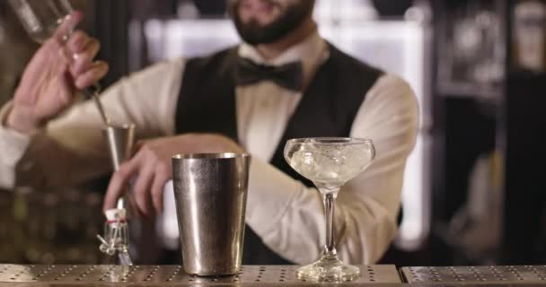 Een close-up opname. De barman giet alcohol uit een fles in een shaker met behulp van een maatbeker. 4K — Stockvideo