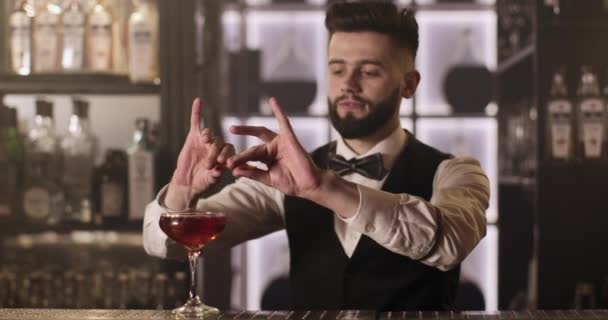 Střední rána. Barman vymačkává kousek pomerančové kůry a zdobí koktejl. 4k — Stock video