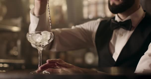 Disparos de cerca. El camarero está girando el hielo en vidrio usando la cuchara de bar. 4k — Vídeo de stock