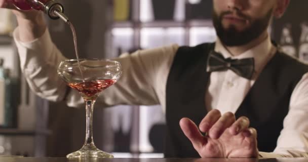 Der Barkeeper gießt ein Getränk aus einer Flasche in ein Glas. 4K. — Stockvideo