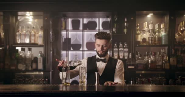 El camarero está vertiendo una bebida de una botella en un vaso. 4k — Vídeos de Stock