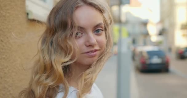 Disparos de cerca. Disparo de retratos. La chica está mirando a la cámara y su pelo está volando en el viento. Está girando la cabeza. 4K — Vídeos de Stock