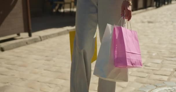 Девушка медленно ходит по городу. Она несет сумки с покупками. 4K — стоковое видео