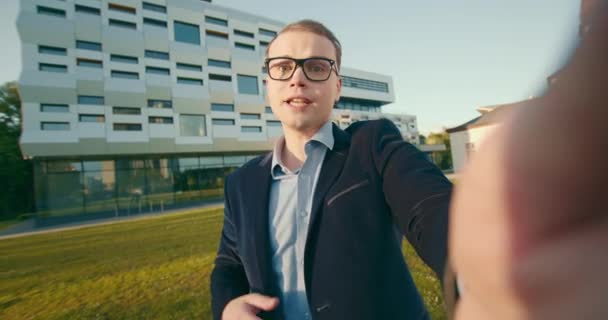 A businessman is emotionally talking through a video link on a smartphone. He is holding a smartphone in his hand. Business center in the background. 4K — Stock Video