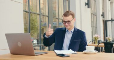 Bir iş adamı video konferansında dizüstü bilgisayarla konuşuyor. O mutlu ve interlocutorlara 