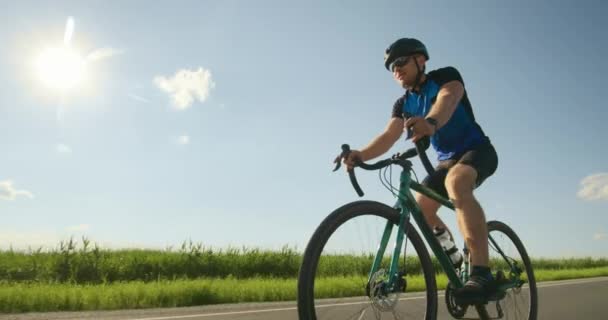 En idrottsman på cykel rider långsamt längs banan. Träning på cykel. Solen skiner i bakgrunden. 4K — Stockvideo