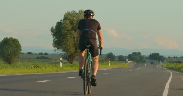 Ein Radfahrer fährt mit langsamem Tempo auf der Autobahn. Training auf dem Fahrrad. Schießen von hinten. 4K — Stockvideo