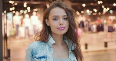 Yakın plan çekim. Kız başını çeviriyor ve kameraya bakıyor. O gülümsüyor. Arka planda saklayın. 4K