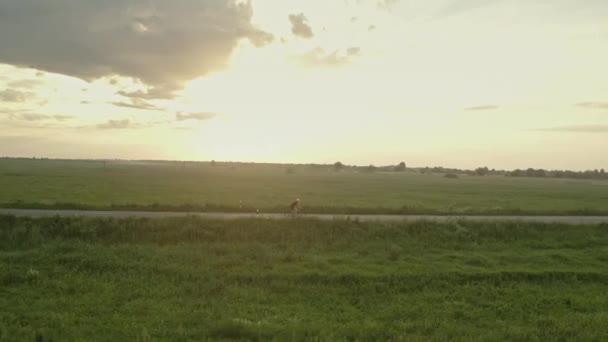 Un deportista está montando rápido en la carretera. Está conduciendo a un lado de la carretera. El dron se acerca a él. 4K — Vídeos de Stock