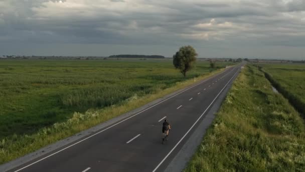 El deportista está entrenando en una bicicleta. Conduce rápido por la autopista. Disparando desde un dron. 4K — Vídeos de Stock