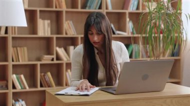 Ciddi derecede güzel beyaz bir kadın rapora dokunurken öne eğiliyor ve yazılı verileri analiz ediyor. Sanal toplantıda sonuçları paylaşmadan önce sunum hazırlanıyor veya numaraları iki kez kontrol ediliyor.