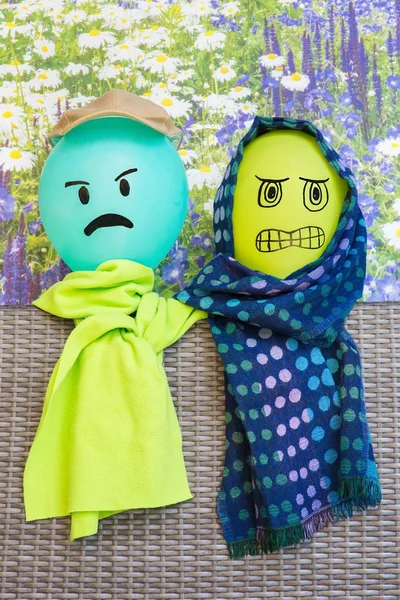 Two balloons with angry facial expression wearing green shawls