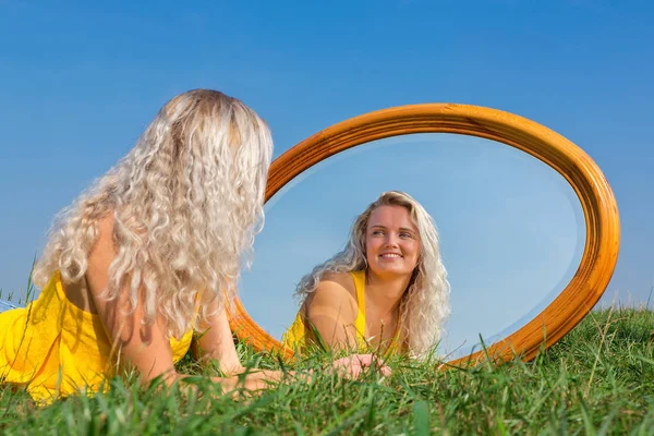 年轻的金发的荷兰妇女躺在与镜子的草 — 图库照片