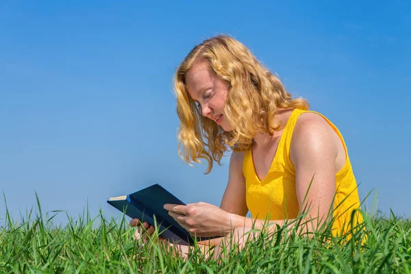 Jonge Kaukasische Vrouw Leest Boek Gras Met Blauwe Lucht — Stockfoto