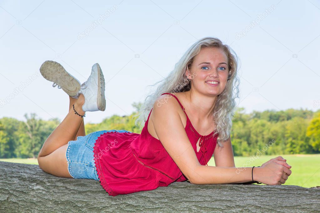 Young caucasian woman lying on tree trunk in nature