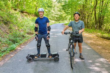 Baba ve oğul dağ bisikleti ve mountainboard yolda ile ayakta