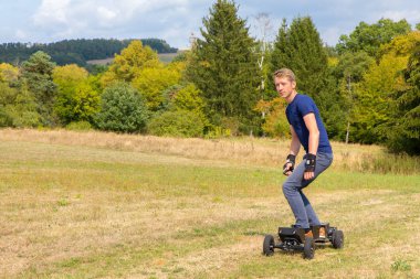 Beyaz delikanlı doğada yoldan elektrik mountainboard rides
