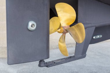 Altın renkli metal pervane ve geminin gri dümen