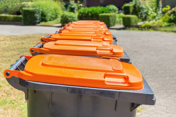 Row of gray with orange waste containers for packaging material along the street