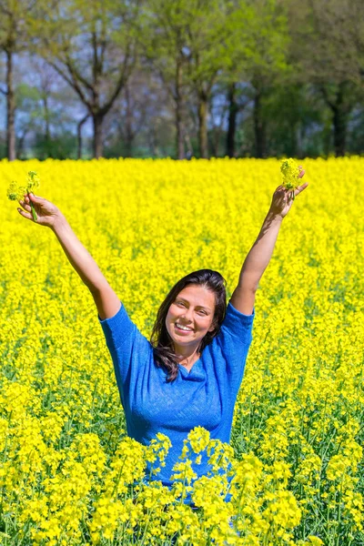 Jovem mulher feliz braços para cima no campo de colza amarelo — Fotografia de Stock