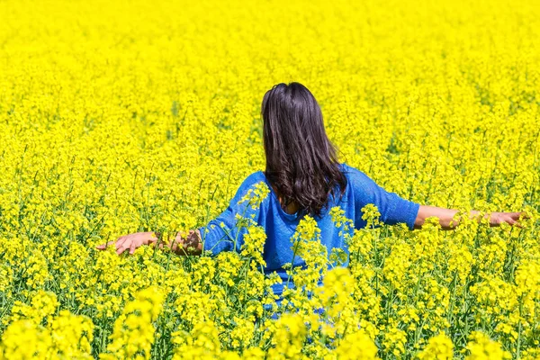 Mulher caminha em florescente campo de colza amarelo — Fotografia de Stock