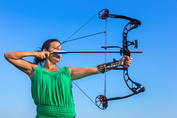 Young colombian woman aims arrow of compound bow