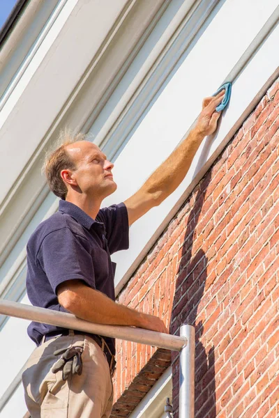 Pintor masculino caucásico limpiando el techo moldeado con tela —  Fotos de Stock