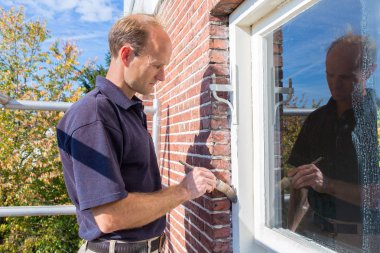 Hollandalı ressam fırça ile pencere çerçevesi boyar