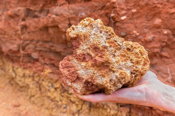 Rust piedra marrón en la mano cerca de la roca — Foto de Stock