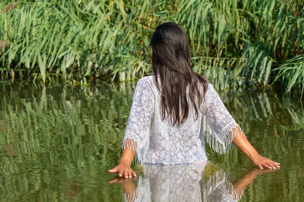 Mujer camina en agua natural cerca de las plantas de caña —  Fotos de Stock