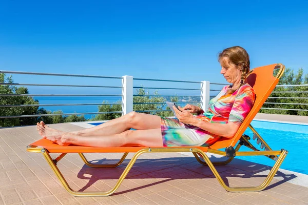 Middle Aged Dutch Woman Lying Orange Sunlounger Reading Tablet Pool — Stock Photo, Image