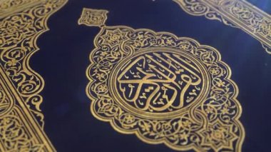 Altın ile süslenmiş Quran mavi kapak, lens parlamaile, alan sığ derinliği yakın-up cgi atış aşağı yavaş eğim.
