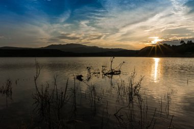 Güneş ışınları ile göle yansıyan unset manzara