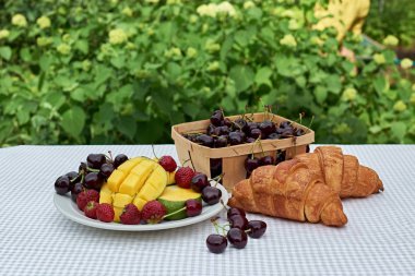 Taze tatlı kiraz, mango ve kruvasan ile meyve salatası masada beyaz arka plan. Düz yatıyordu, konsept kompozisyon brackfast