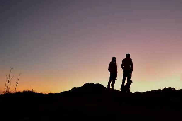 Oğluyla birlikte bir sırtta köpekleriyle güneşin doğuşunu izleyen bir baba