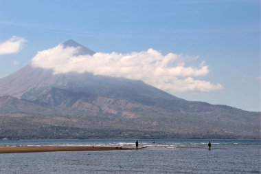 Sulawesi, Endonezya bulutlar ile yüksek bir yanardağ önünde bir gölün su Balıkçılar.