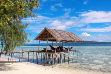 Güneşli bir günde Raja Ampat tropikal bir plajda su üzerinde hamaklar ile Stilt platformu.