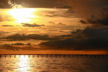 Papua Yeni Gine yakınlarındaki okyanusta ahşap iskele üzerinde gün batımı, güney-doğu Asya.