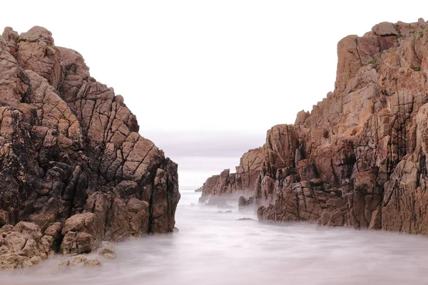 LONG EXPOSURE PHOTOGRAPH ON A BEACH BETWEEN TWO CLIFFS
