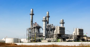 Mavi gökyüzü arka planında elektrik santrali inşaatı ve endüstriyel boru sistemi