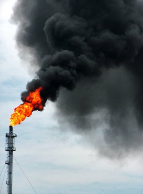 Petrol rafinerisinden yükselen ateş ve duman. Petrol sınırlı hale geliyor ve dünya dünyayı daha temiz hale getirmek için yenilenebilir enerji aramaya başladı..