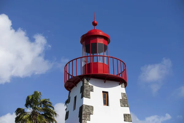 Tower of a red and white lighthouse with blue sky background.