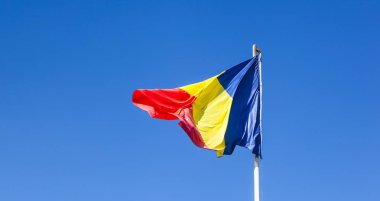 Romanya bayrağı direği üzerinde. İpek Romanya bayrağı. Romanya bayrağı bayrak direğine mavi gökyüzü ile boşaltmak izole rüzgarda üfleme.