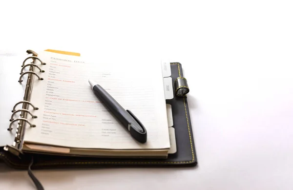 Organizer boek open op een lege formulierpagina op de witte achtergrond met een zwarte pen — Stockfoto