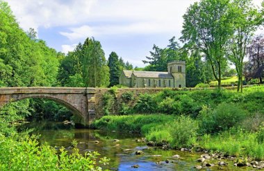 Askham, Penrith, Cumbria, İngiltere'de Askham Köprüsü ve St Peter Kilisesi'ni içeren bir İngiliz köyü pastoral sahnesi yakalamak.