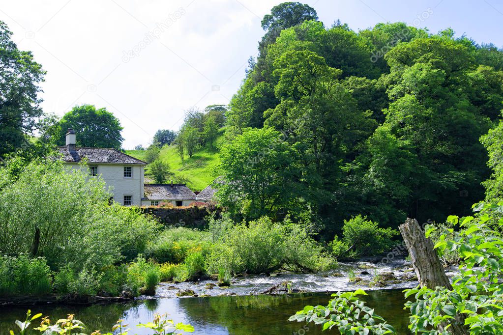 Capturing a quintessentially English village pastoral scene, incorporating a country cottage beside the River Lowther, in Askham, Penrith, Cumbria, England.