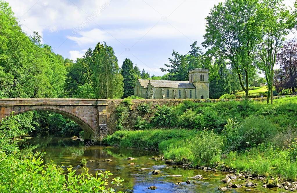 Capturing a quintessentially English village pastoral scene, incorporating Askham Bridge and St Peter's Church, in Askham, Penrith, Cumbria, England.