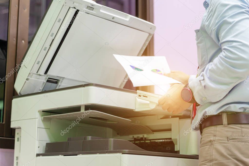 Men press the button of the copier. Man copying paper from Photo