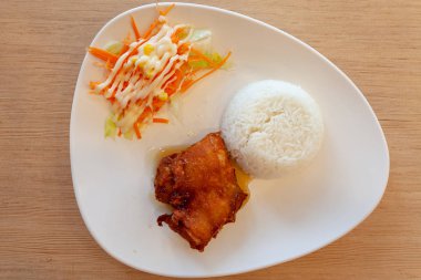 Pirinç ve kızarmış tavuk renkli bir tabakta, pirinç ahşap bir masada